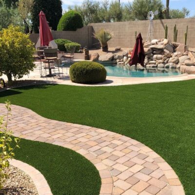 plants and artificial turf backyard with a paver pathway