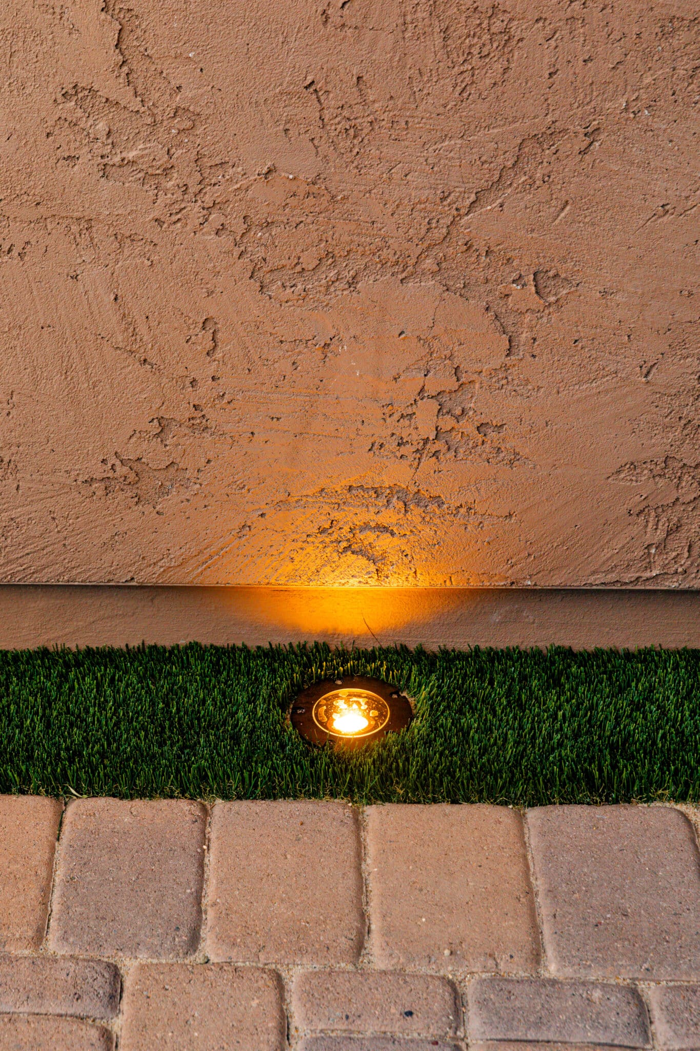 Lighting hidden in artificial turf with wall and pavement