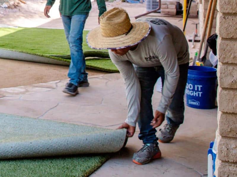 Workers installing fake grass in customer's backyard