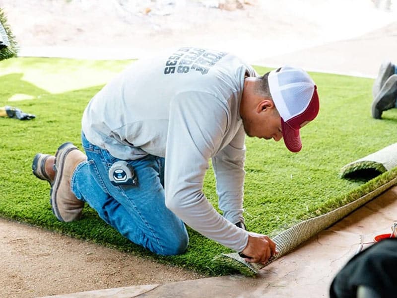 Employee cutting fake grass to fit backyard