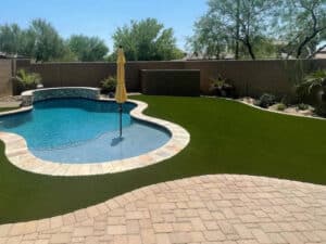 Custom installed pavers and faux turf surrounding pool